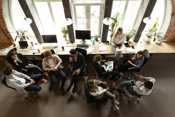 Young men and women discussing something with coworkers, sitting at office table