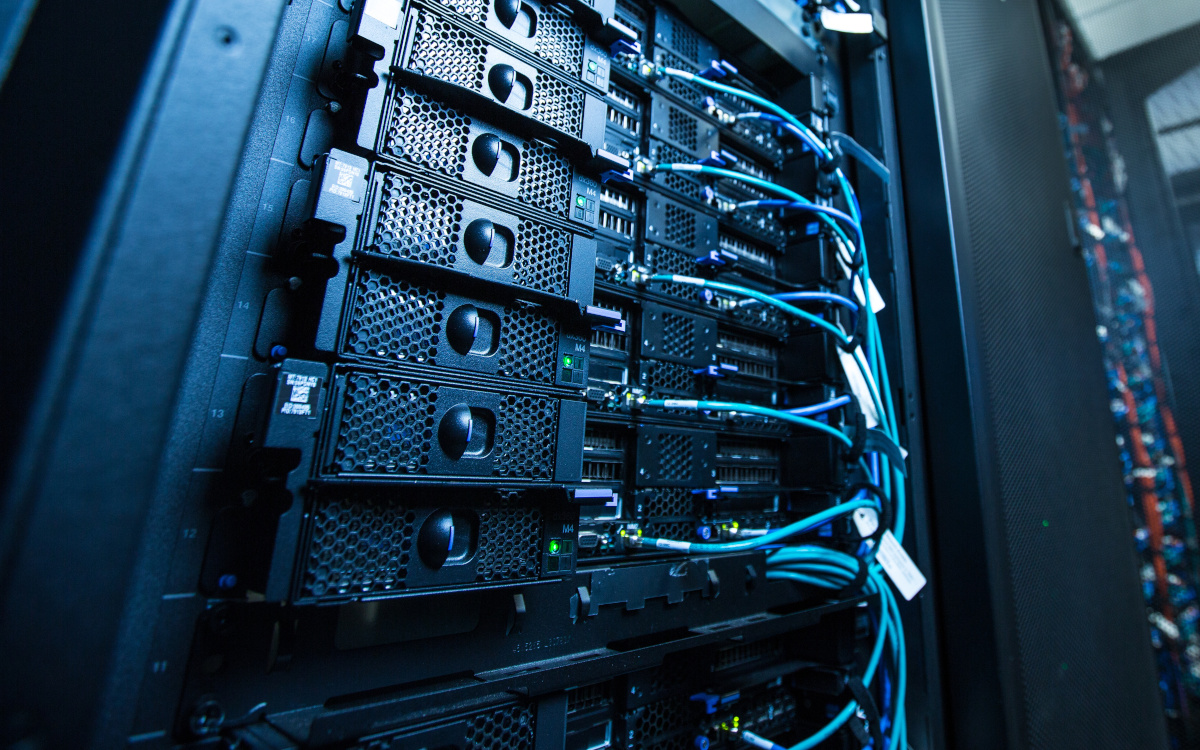 Data center technician working on a rack of servers with blue and orange cables